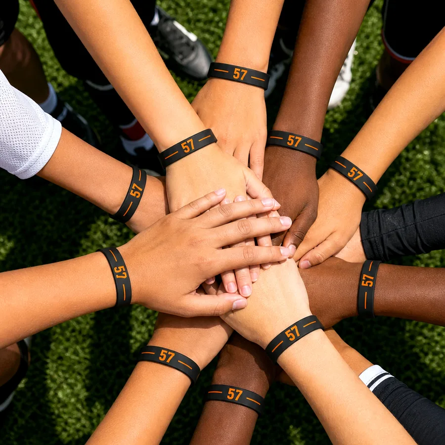 Athletes stacking wristbands together as a team commitment cue